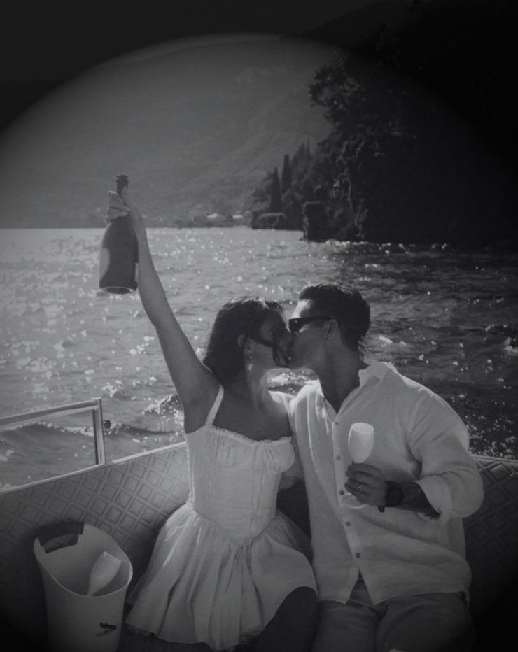Pareja brindando en una lancha frente a un lago, en blanco y negro