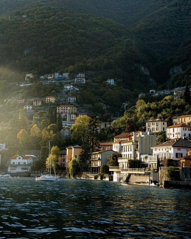 Pueblo a orillas de un lago entre montañas, con luz de tarde