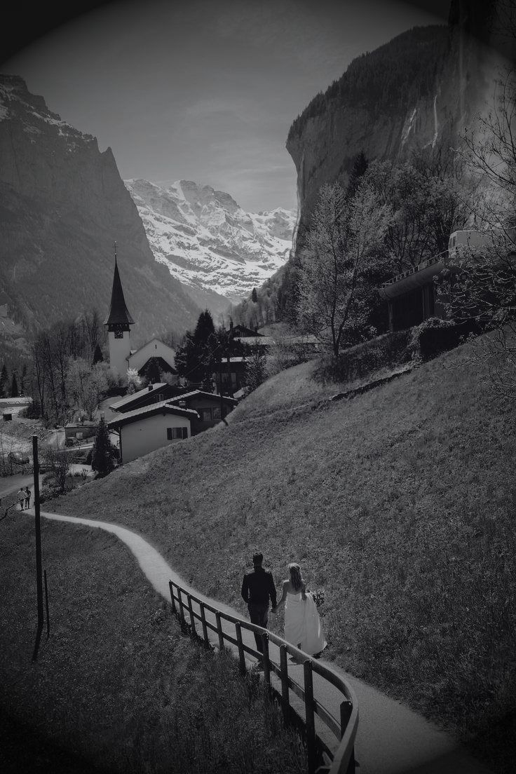 Novios caminando por un valle entre montañas, en blanco y negro