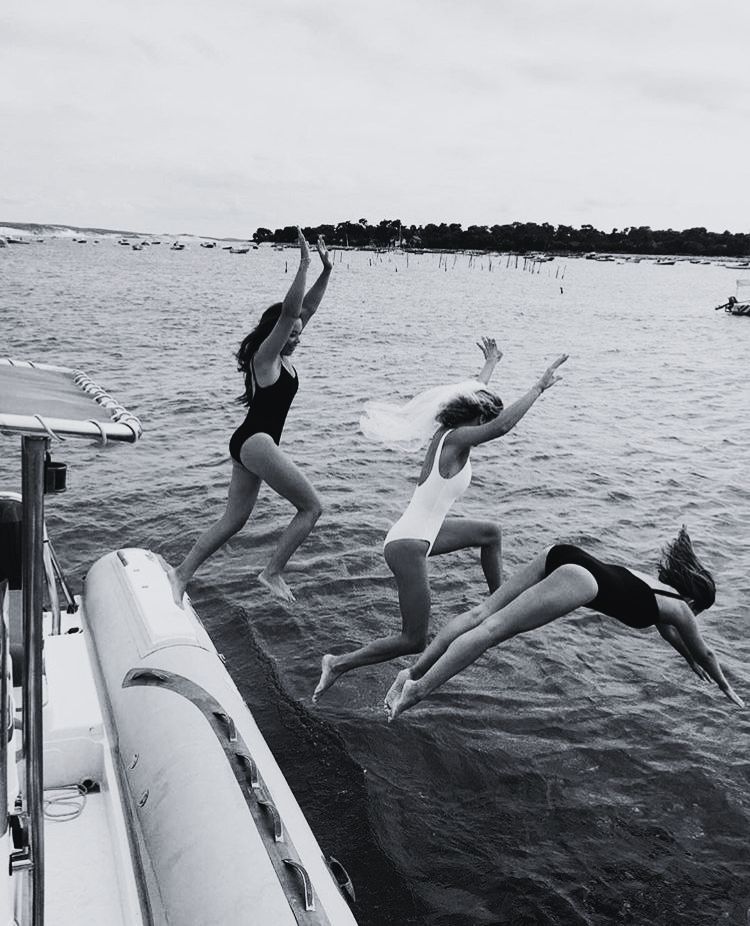 Amigas saltando al agua desde un barco